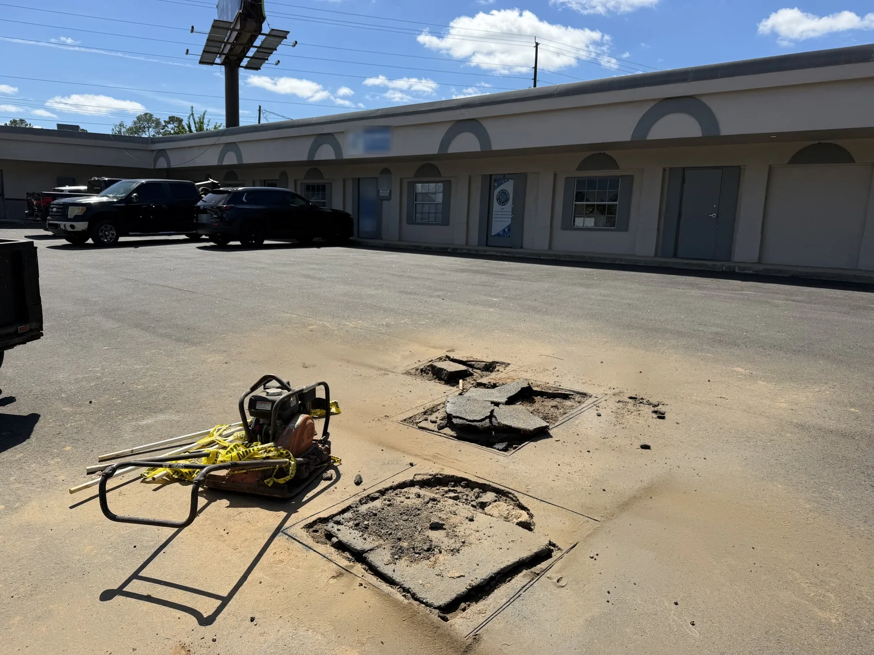Broken asphalt at a saw cut utility patch in a commercial parking lot before repair