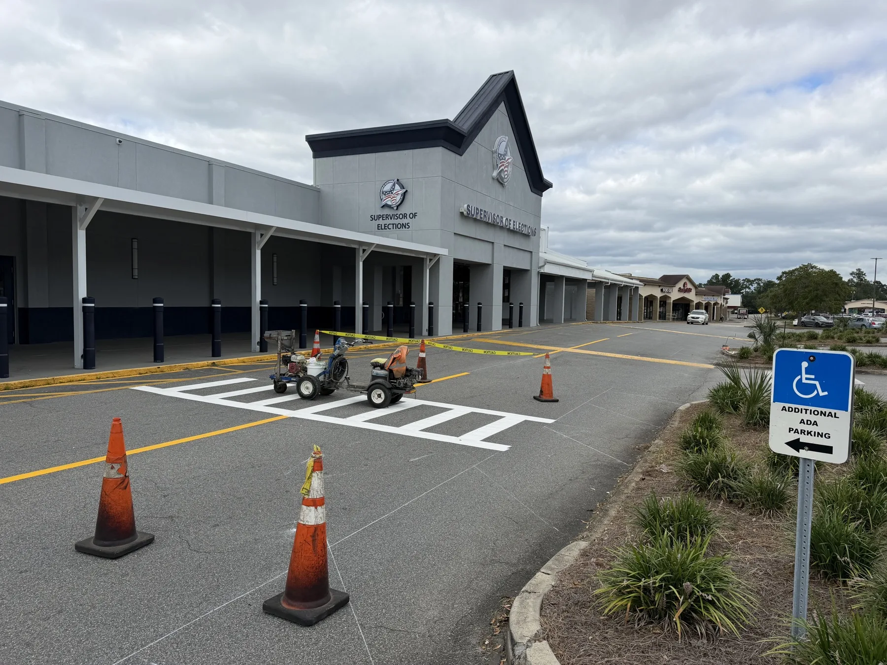 Line striping machine and cones beside a freshly painted crosswalk at the Leon County Supervisor of Elections